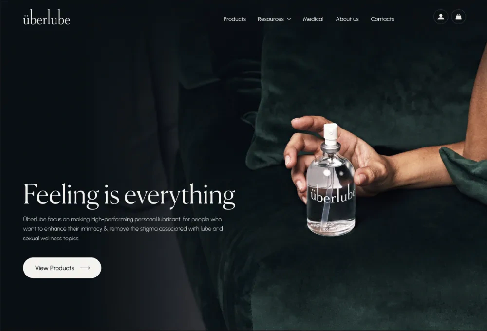The Überlube homepage after the redesign: Feeling is everything beside a hand holding the bottle, on a dark green background