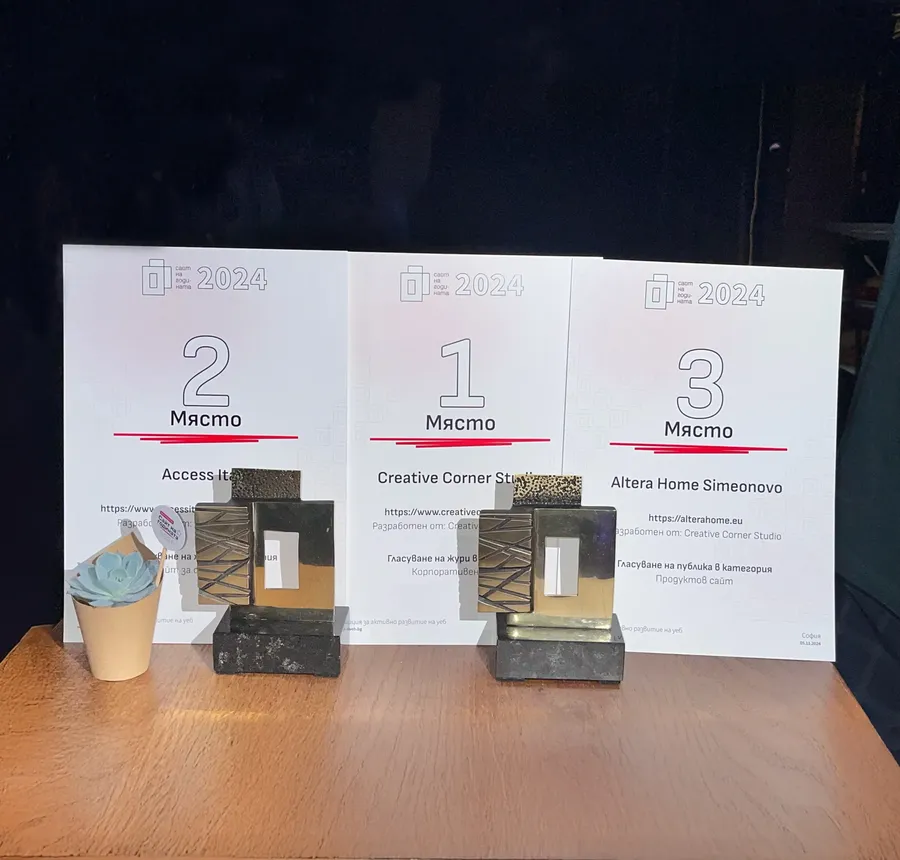Three awards on a wooden surface with certificates behind them showing 1st, 2nd, and 3rd place for Creative Corner Studio, Access It, and Altera Home Simeonovo respectively.